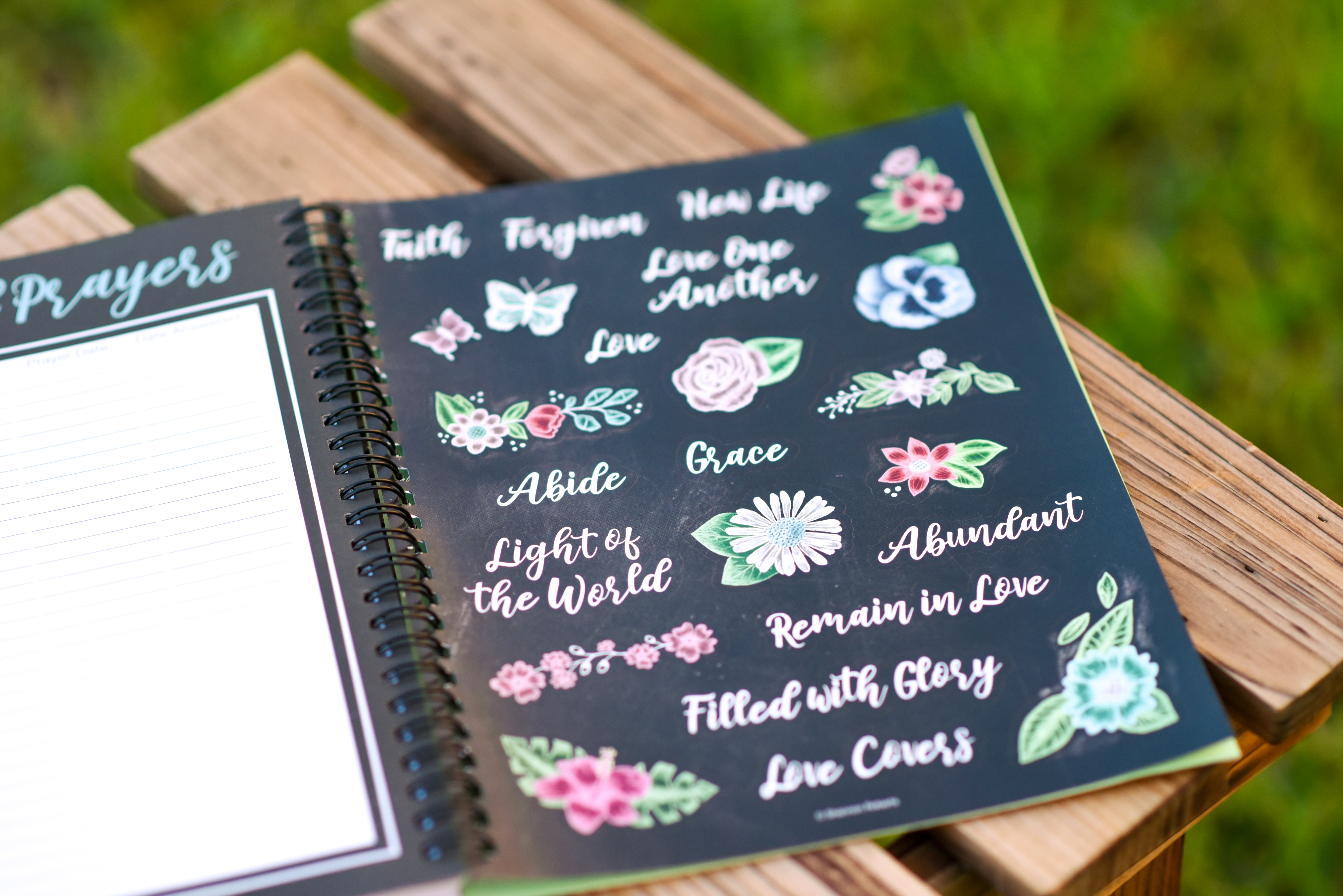 2026 prayer journal for women planner with decorative stickers featuring floral and motivational text on a wooden surface.