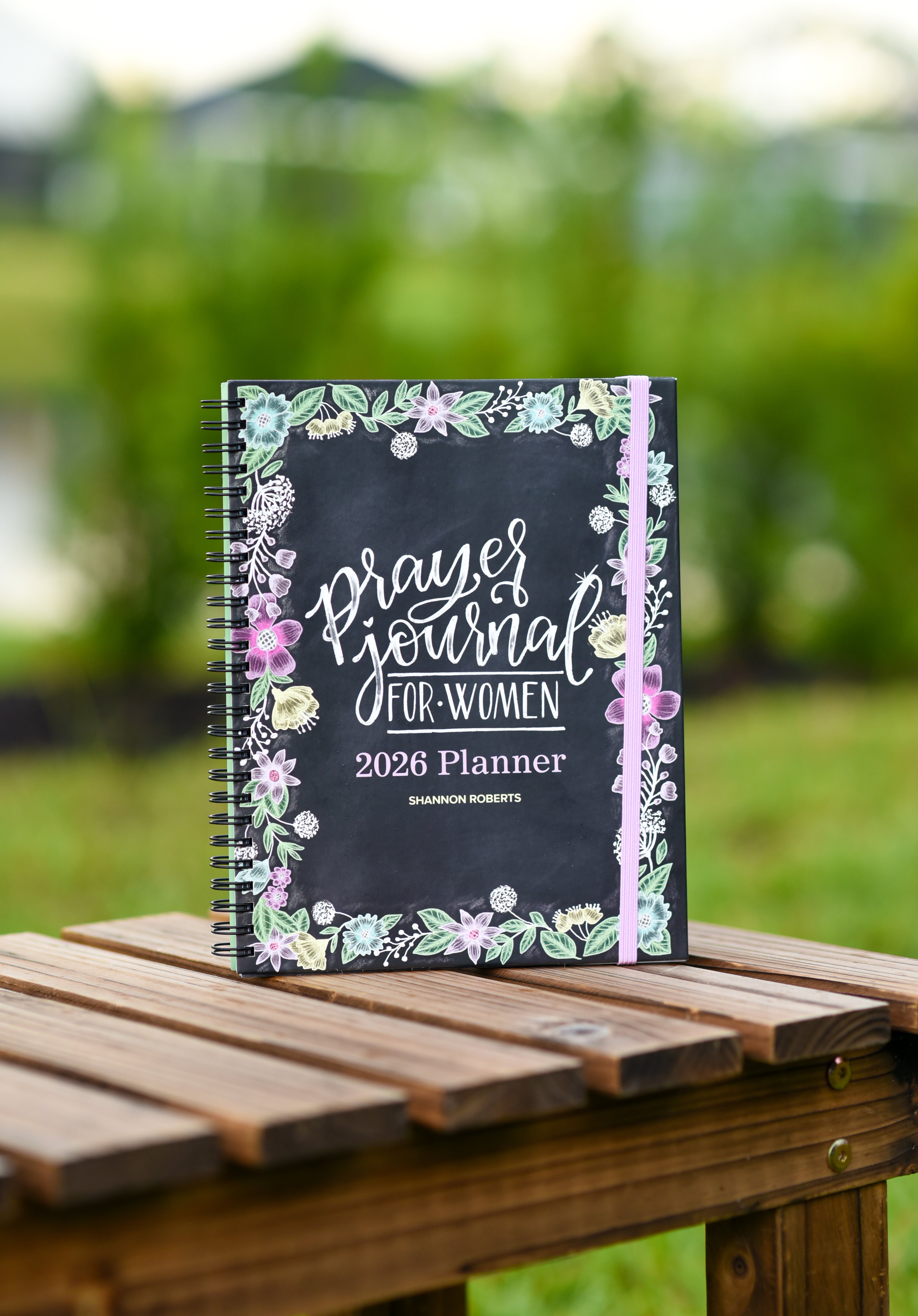 2026 prayer journal for women planner for women on a wooden table with a blurred green outdoor background