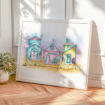 Framed artwork of colorful beach houses on a wooden surface