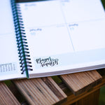 Open planner with prayer requests on a wooden surface outdoors