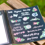 2026 prayer journal for women planner with decorative stickers featuring floral and motivational text on a wooden surface.
