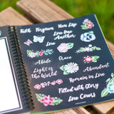 2026 prayer journal for women planner with decorative stickers featuring floral and motivational text on a wooden surface.
