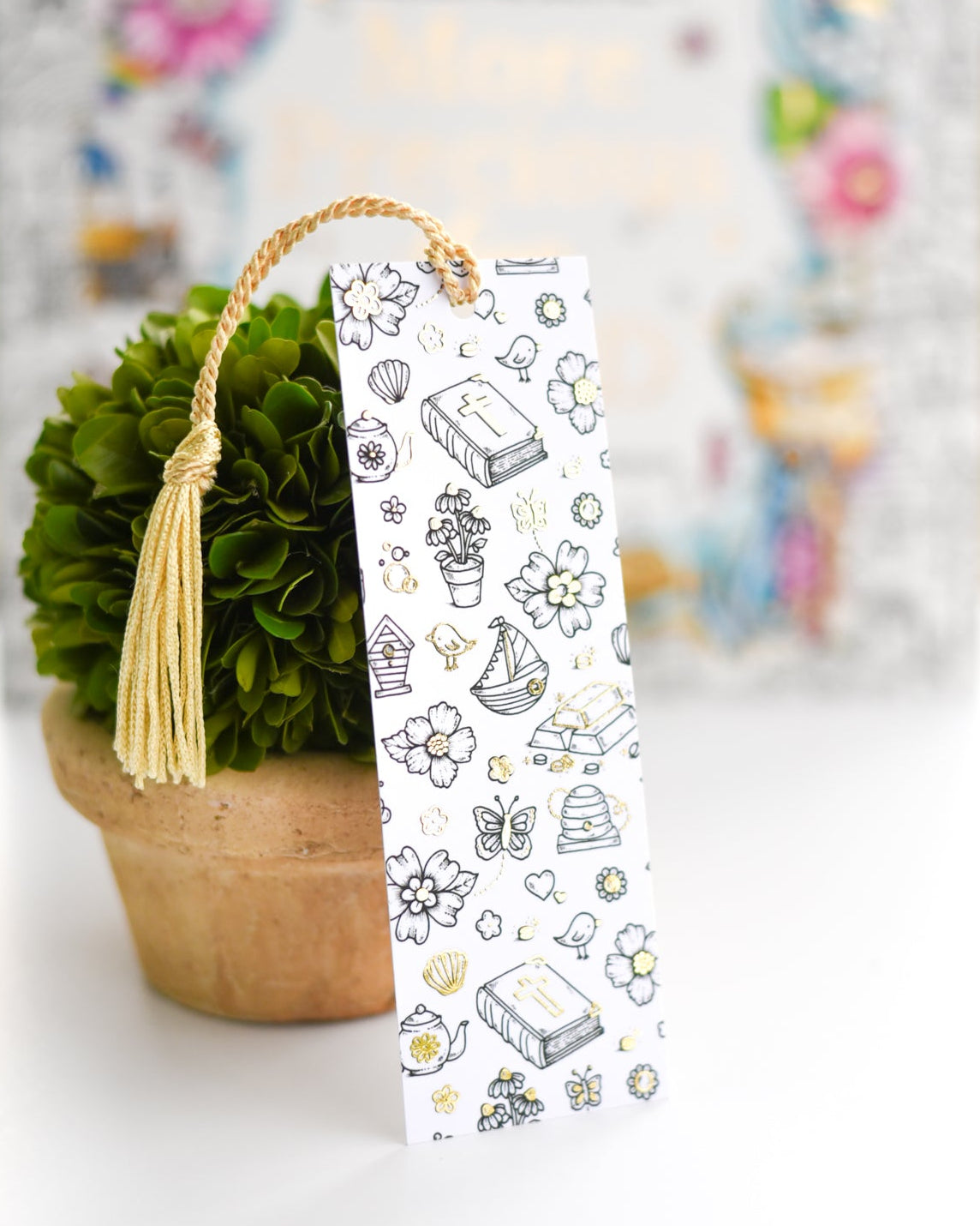 Decorative bookmark with illustrations in front of a blurred floral arrangement
