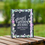 2026 prayer journal for women planner for women on a wooden table with a blurred green outdoor background