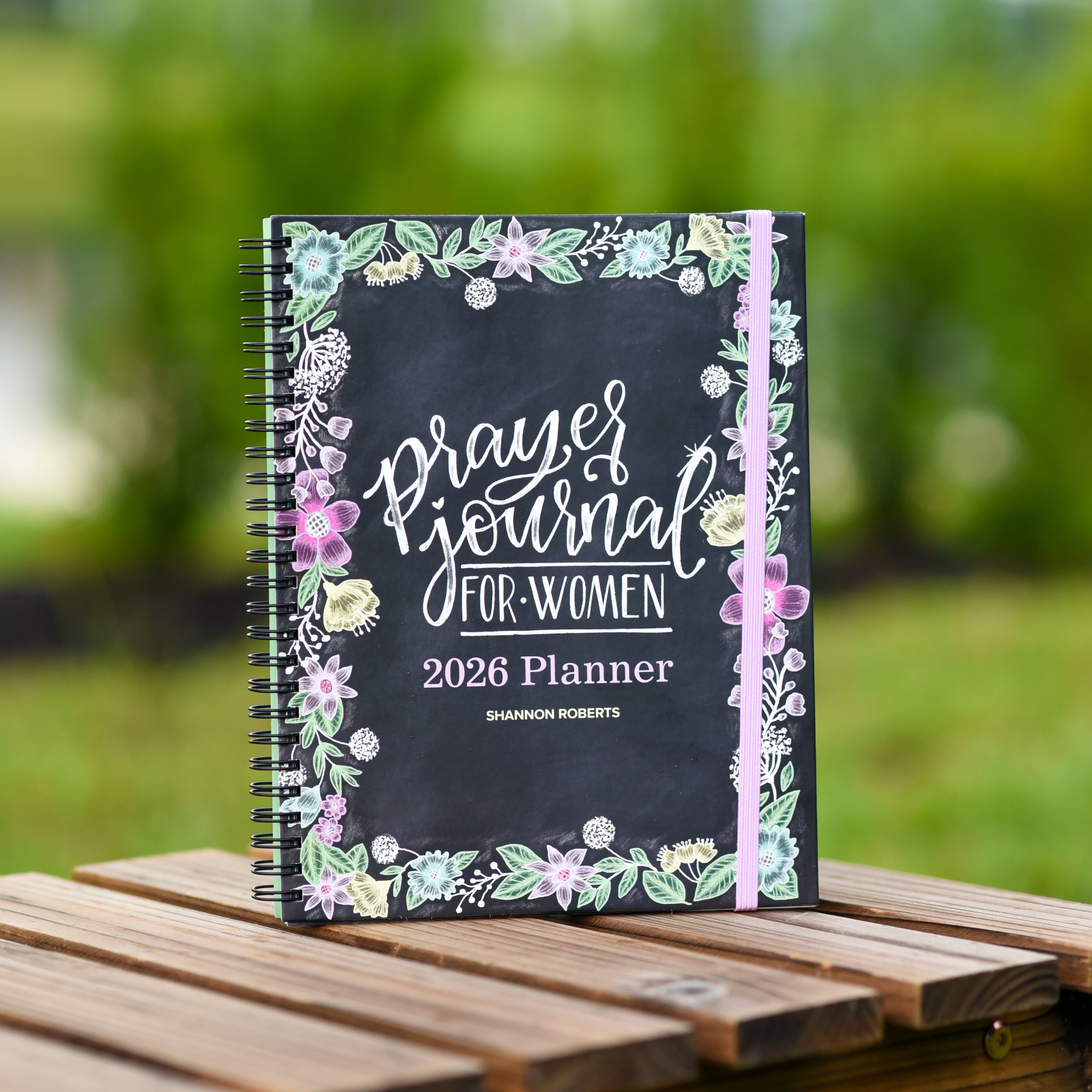 2026 prayer journal for women planner for women on a wooden table with a blurred green outdoor background