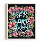 Framed artwork with floral design and 'Rejoice in the Lord always' text on a black background