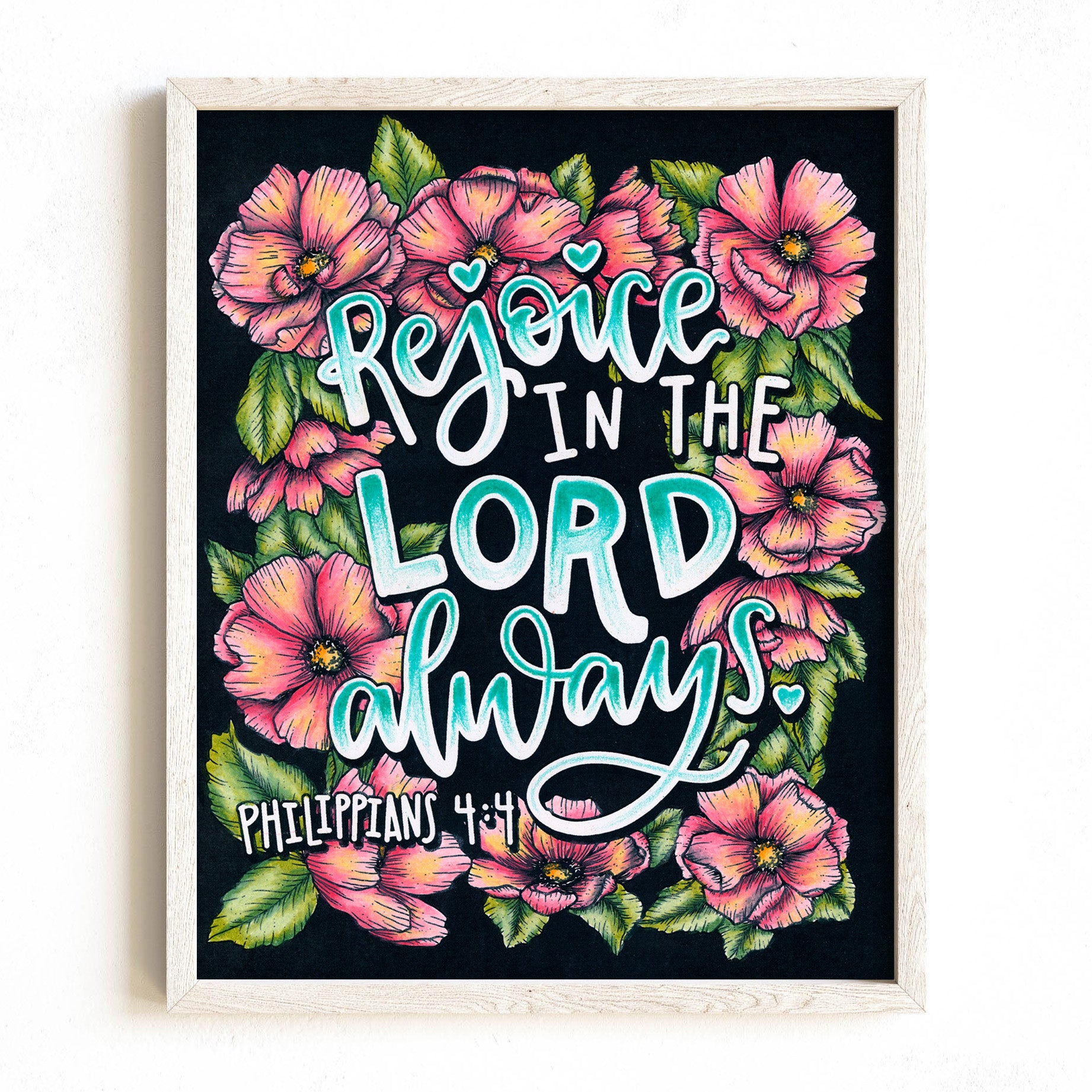 Framed artwork with floral design and 'Rejoice in the Lord always' text on a black background
